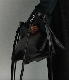A black handbag slung over a model's arm.
