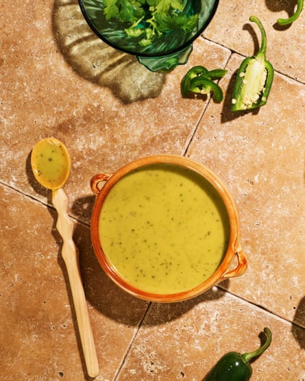 A dish of guacamole falso, a light yellow-green sauce, with a wooden spoon next to it.