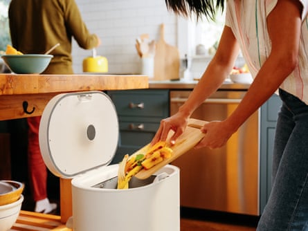 woman emptying food scraps into a bin in a kitchen