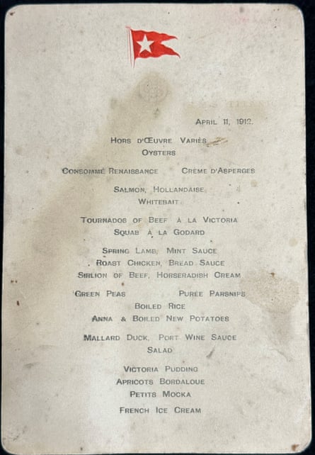 The whole of the waterstained menu revealing all the courses, and showing a red embossed flag with a white star on it at the top