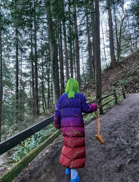 woman walking in woods with long, colorful puffer coat
