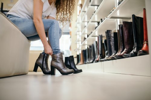 Close up of a woman bending over to try on boots in a shoe store