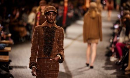 A model wearing a brown suit walks the catwalk