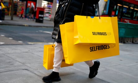 A shopper carries bags from department store Selfridges along Oxford Street, December 2020.