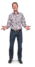 Adrian, standing, wearing a flowery shirt and jeans.