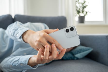 Person lying on couch holding a phone which is blocking a view of their face