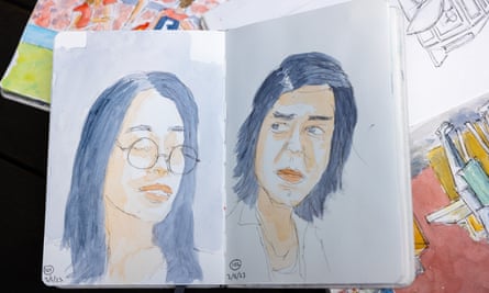 Two watercolour portaits in a sketchbook sitting on top of other sketchbooks. 