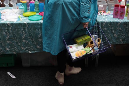 A woman carries a shopping basket containing baby items