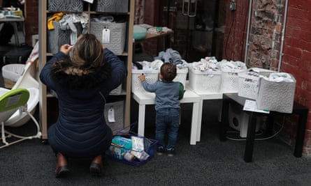 A woman and toddler look through boxes of baby clothes