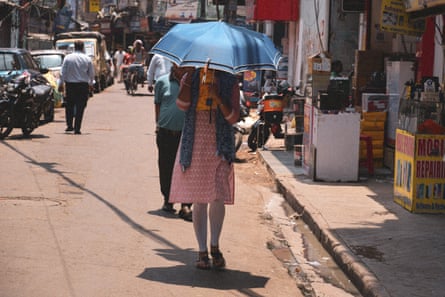 A woman uses an umbrella as a sunshade on a street in Kolkata, India