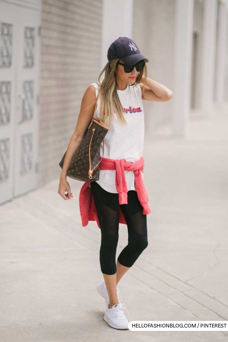 Trendy urban outfit with white tank top, black leggings, and baseball cap.