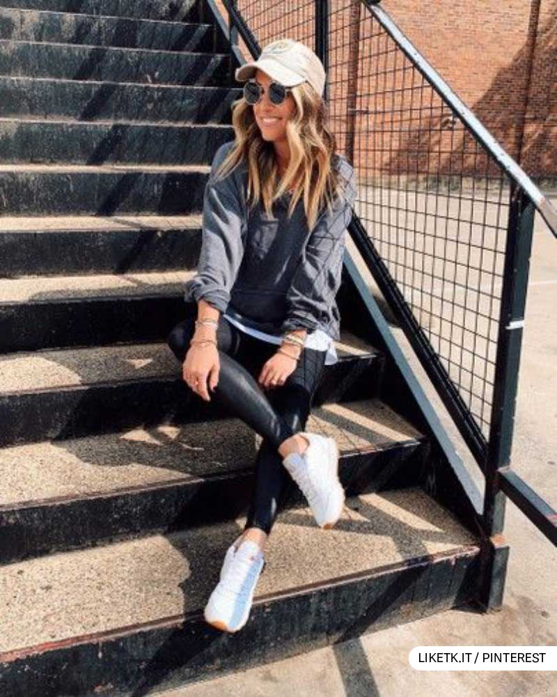 Trendy woman in casual outfit with sunglasses sitting on urban stairway.