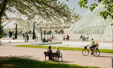 Visitors sitting on a bench, cycling along a pathway and enjoying the sunshine at the cultural and architectural complex.