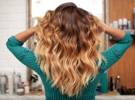 Hair coloring gradient from light golden to brown on a girl with long curly hair in the back