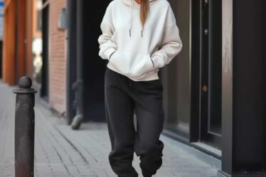 Chic urban outfit with black sweatpants, white hoodie, and black sneakers, complemented by sunglasses.