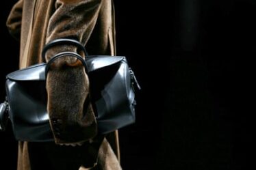 A model on the runway with a leather bag tucked under their arm