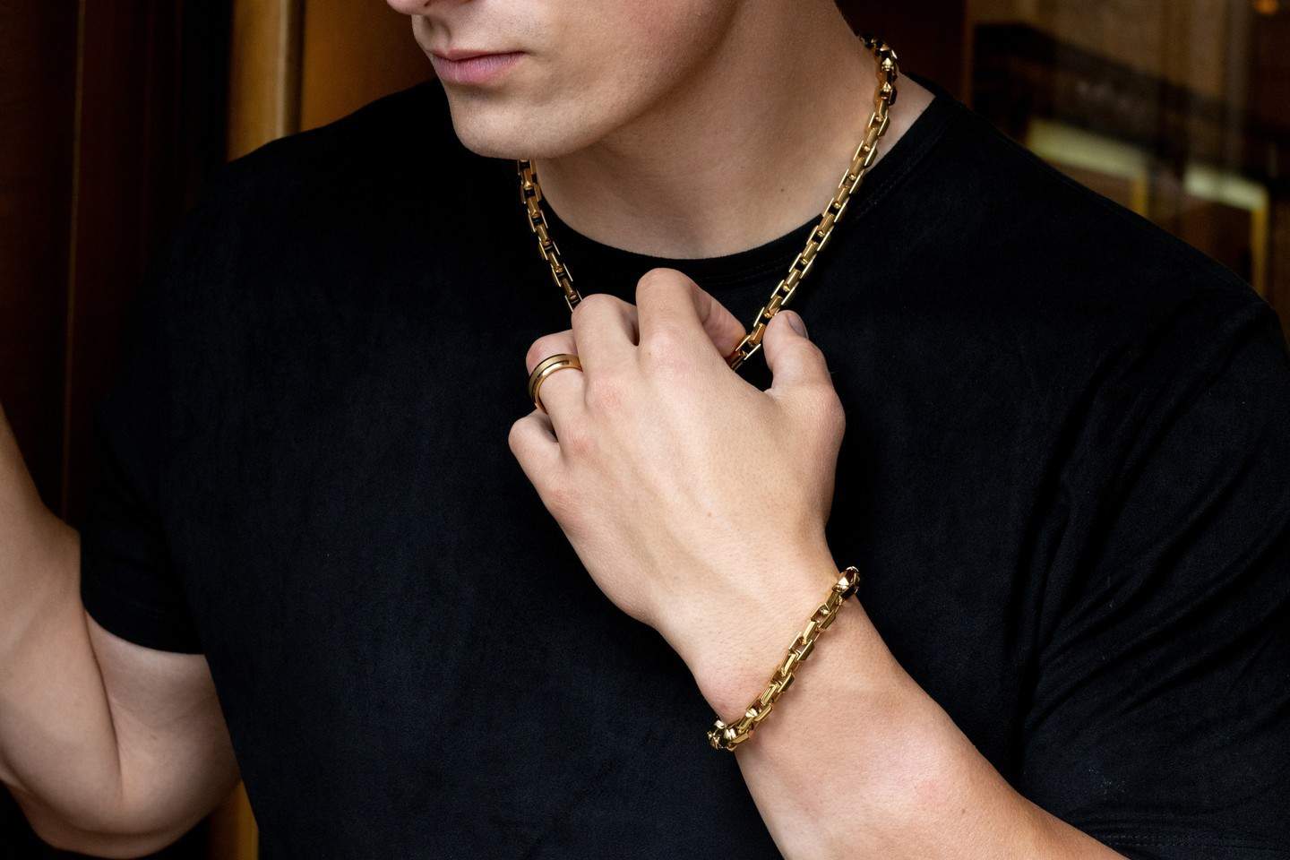 man in a black t-shirt grabbing a chain necklace