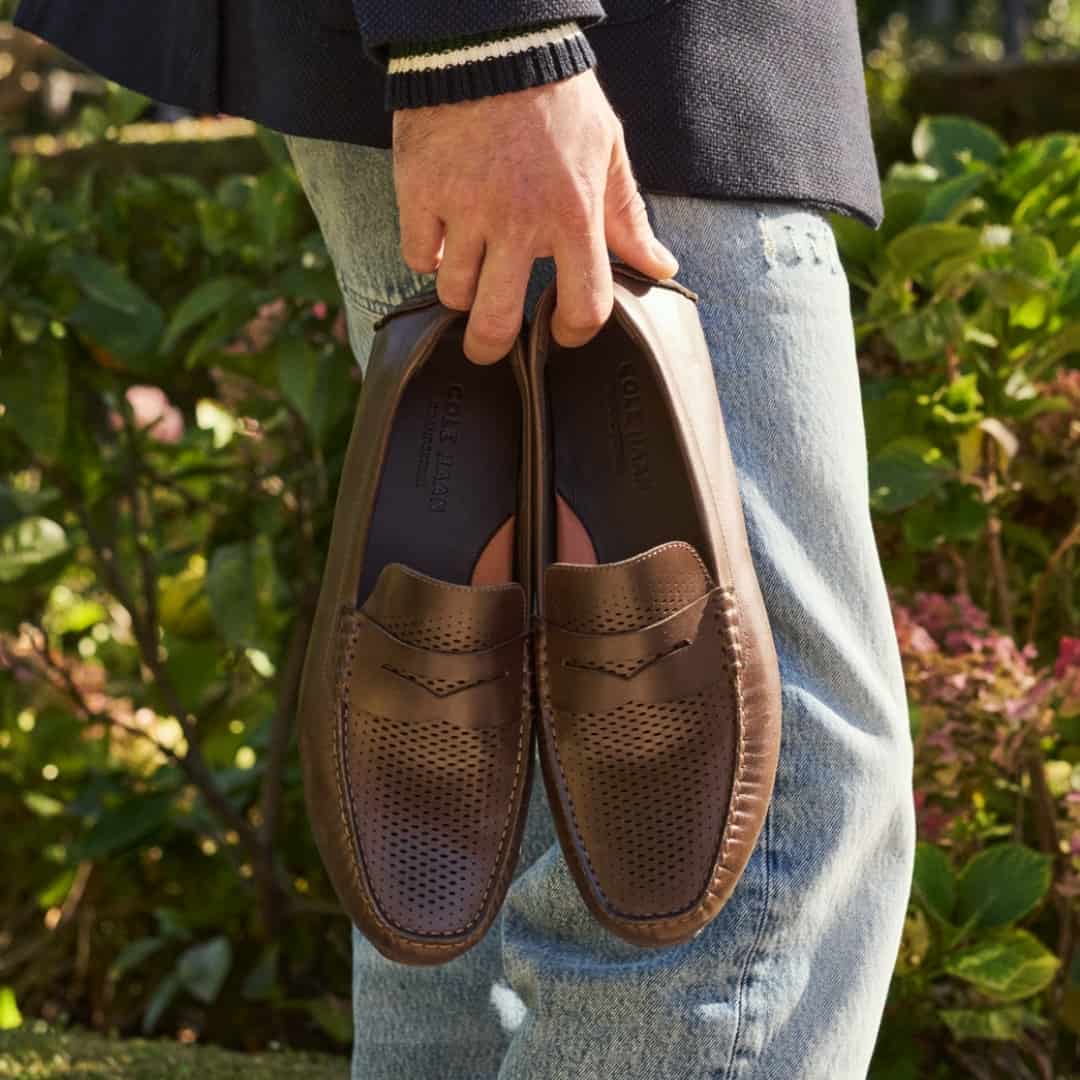 man carrying a pair of driver loafers by cole haan
