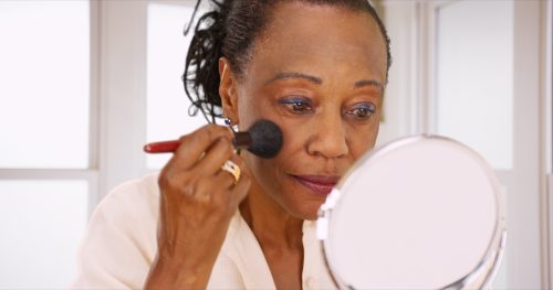 woman applying makeup using makeup mirror