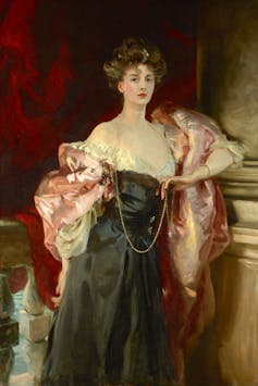 A lady in black gown with a billowing pink cape.