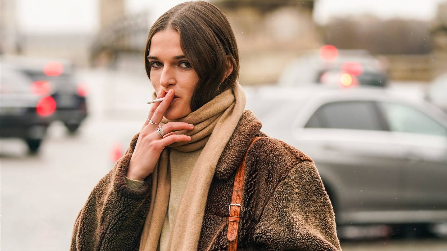 A model wears a light brown wool scarf, a brown fluffy bomber jacket, a brown leather bag, outside Chloe, during Paris Fashion Week.