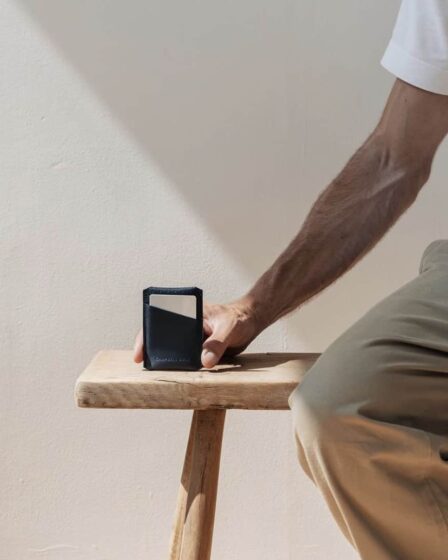 man sitting on a bench showing off a small wallet