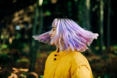 Portrait of confident, young, modern teenage girl with pink, blue hair in nature forest, Germany