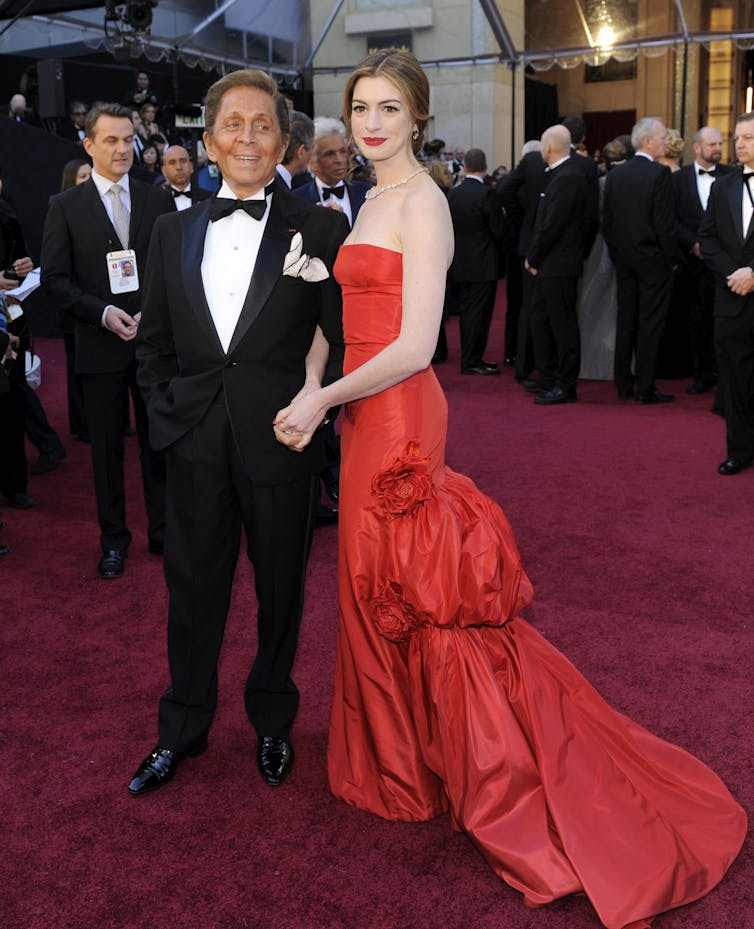 A woman in a red dress and a man in a tuxedo.