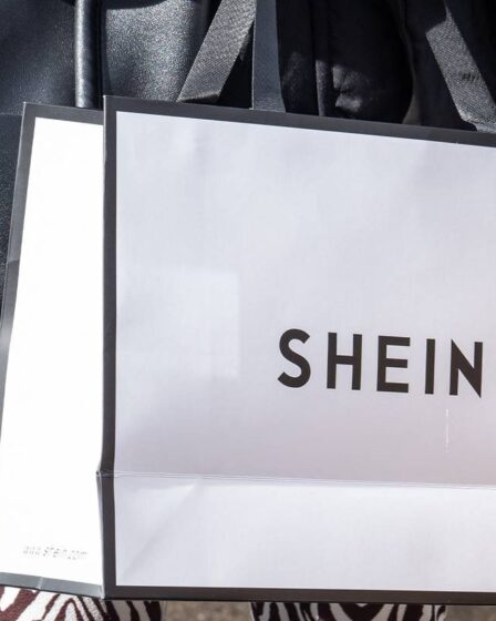 A shopper carries a white Shein shopping bag.