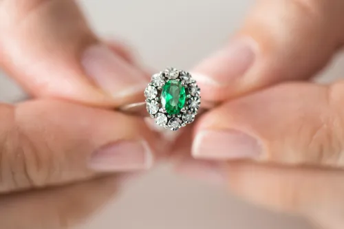 hands holding emerald and diamond ring
