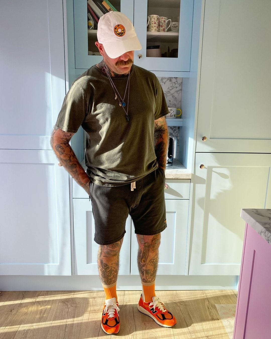 man wearing tall socks with shorts, standing in a kitchen