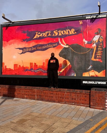Kofi Stone standing in front of a billboard advertising his music, in which he appears as a king with a banner reading ‘It’s Brum town where you’re finding me’.