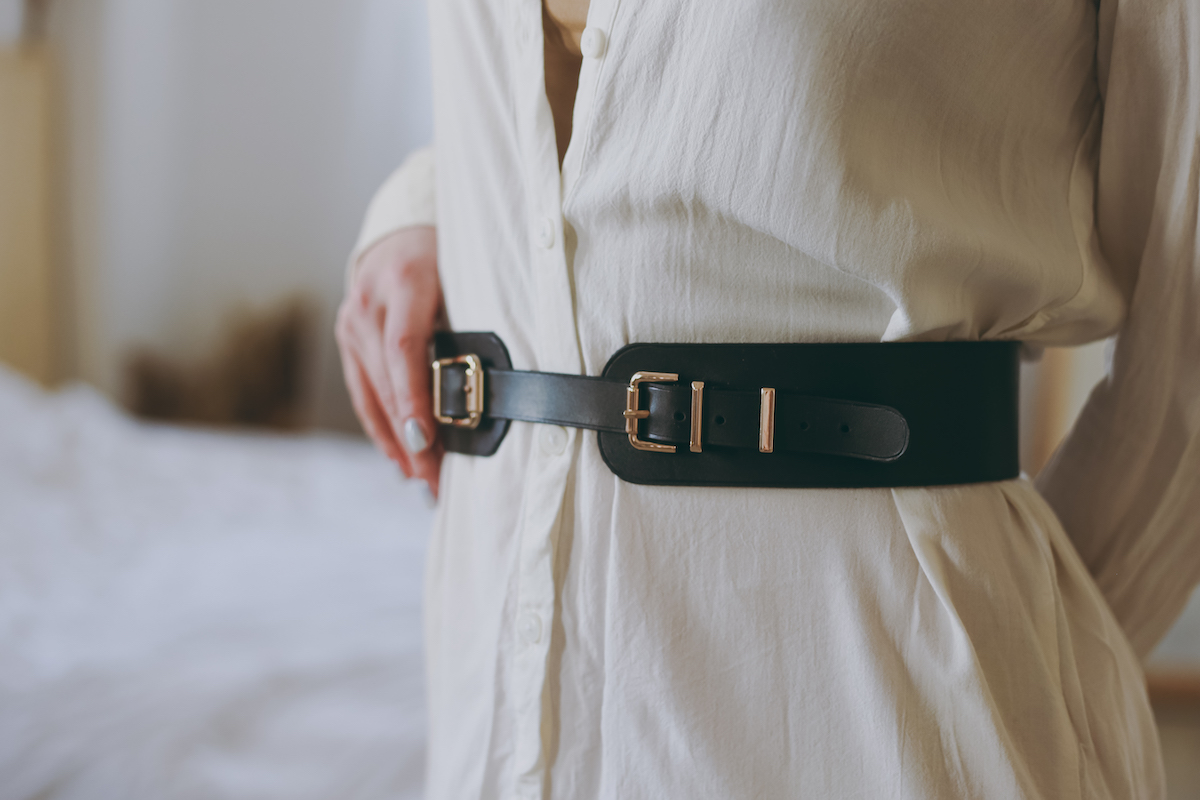 Closeup of woman's torso wearing white shirt and belt