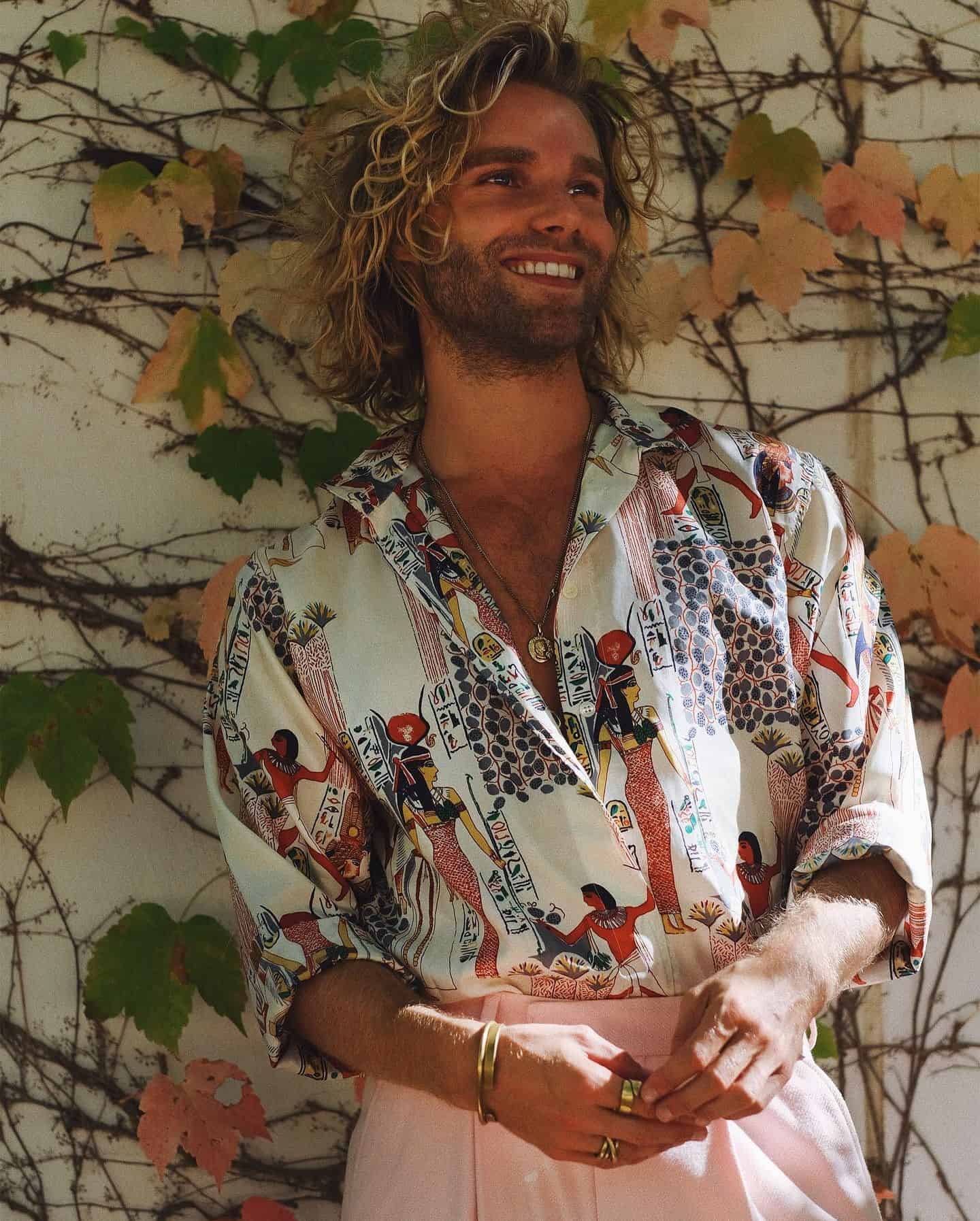 man with long frizzy hair wearing a printed shirt