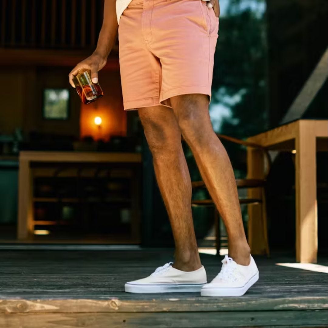 image of a man from the waist down wearing peach-colored shorts with white canvas sneakers on his feet