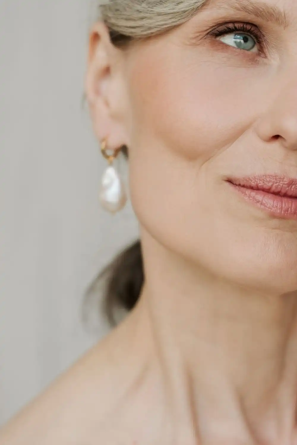 Close-up of older woman wearing pearl earrings.