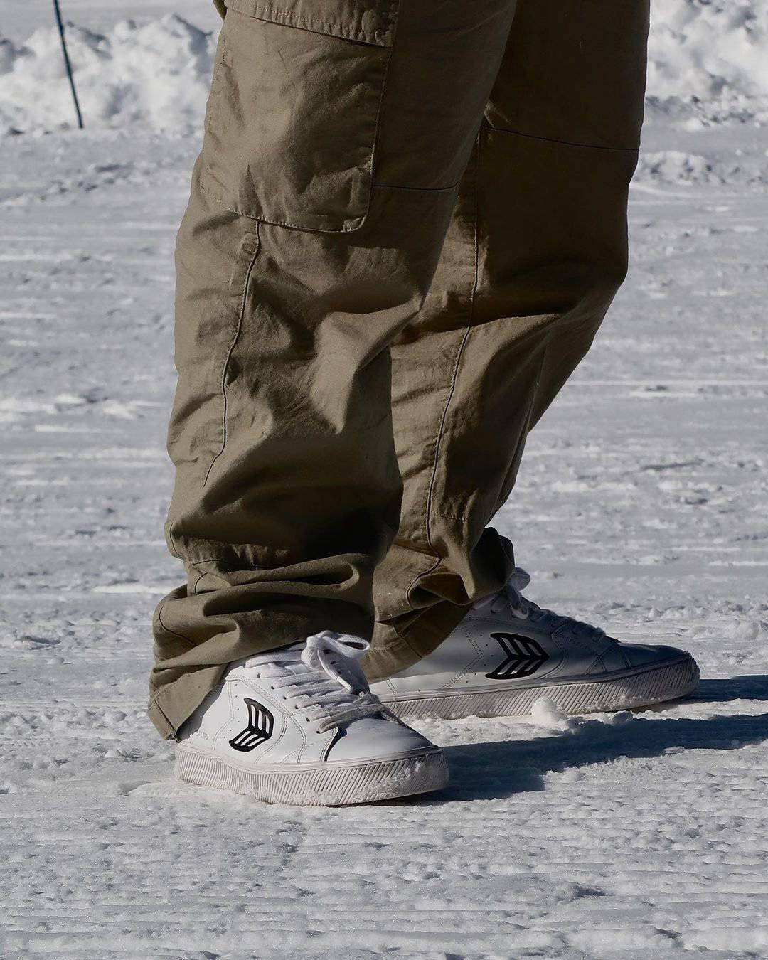 standing on snow with a pair of white sneakers