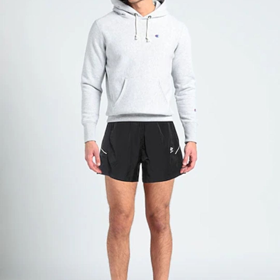 image of a man from the neck down wearing a grey hoodie sweatshirt and black soccer shorts