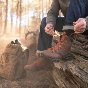 man tying up his waterproof boots in the woods