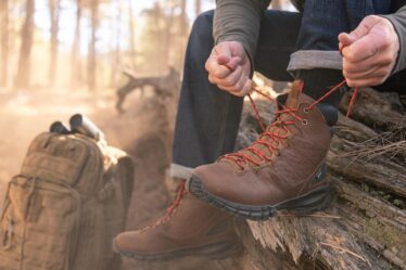 man tying up his waterproof boots in the woods