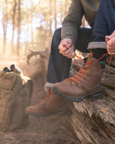man tying up his waterproof boots in the woods