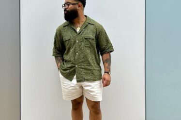 man wearing a short-sleeve green shirt with khaki shorts and black loafers