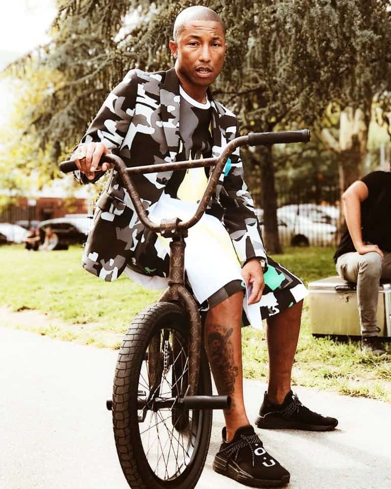 pharrel williams sitting on a bike