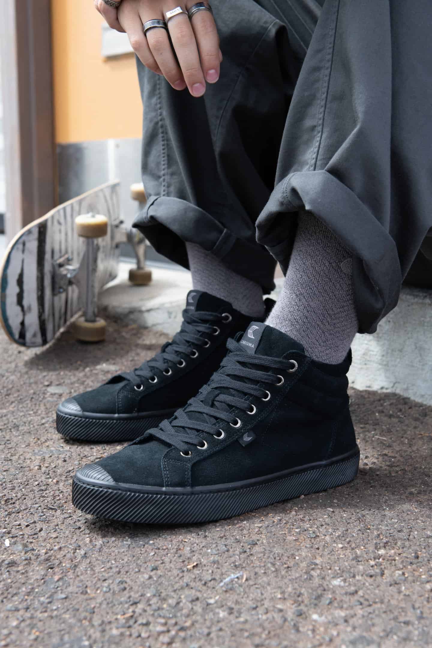 wearing a pair of all black cariuma high tops