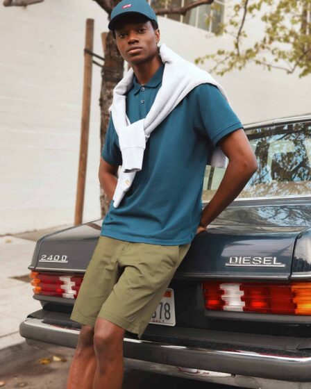 man leaning on a car wearing polo shirt and shorts