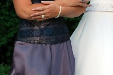 Shoulder to hip view of two women in formal dresses walking side by side.