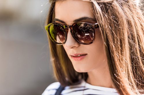 closeup of a young, brunette woman wearing large sunglasses