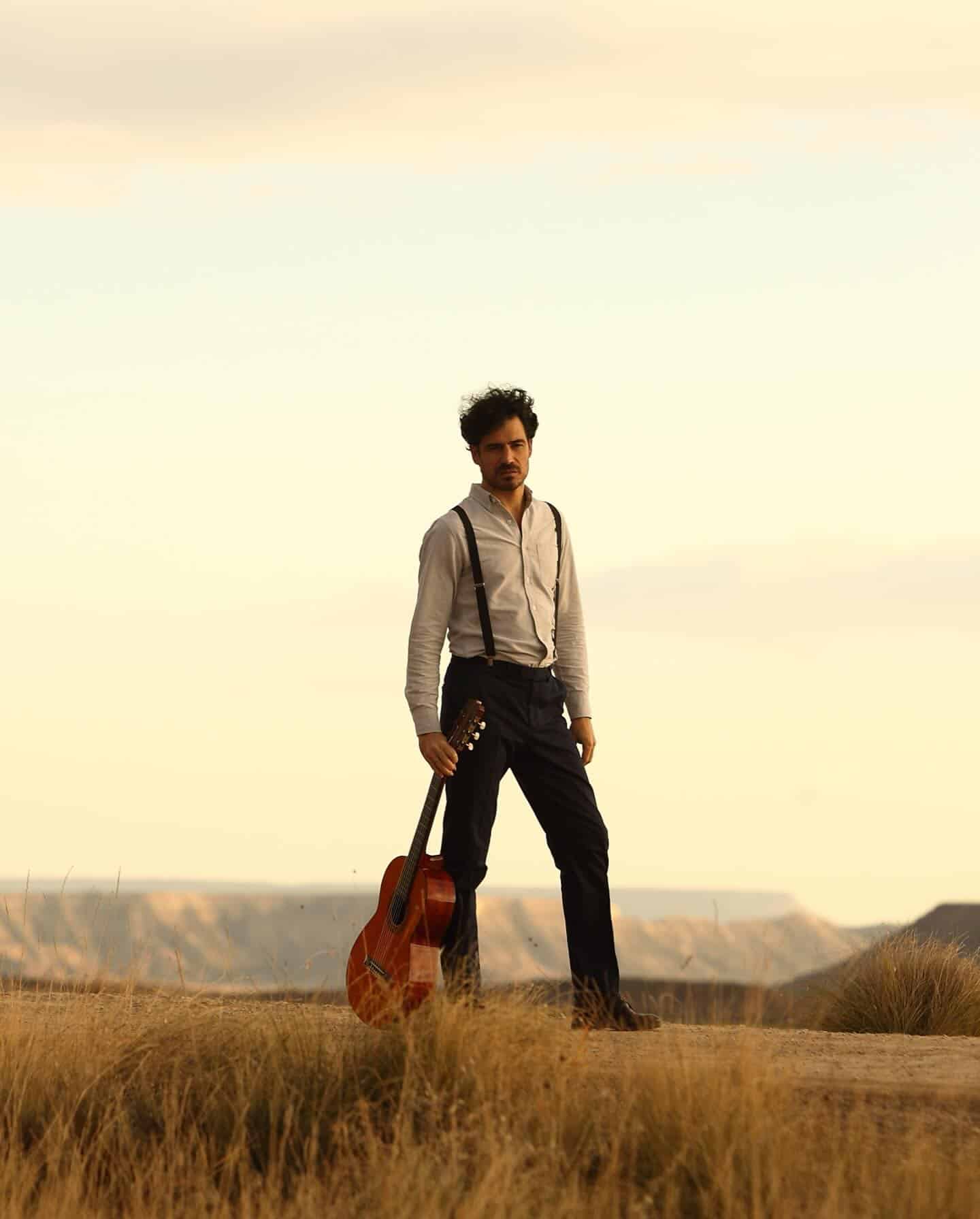 man walking on the road and carrying a guitar