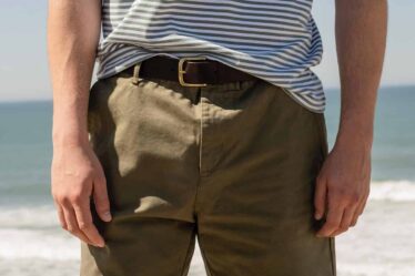 man by the beach wearing a striped shirt and olive shorts