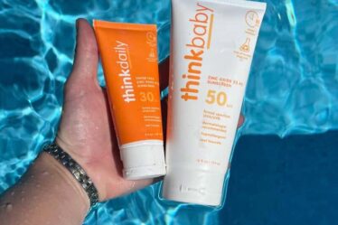 holding bottles of thinkdaily and thinkbaby sunscreen with zinc oxide